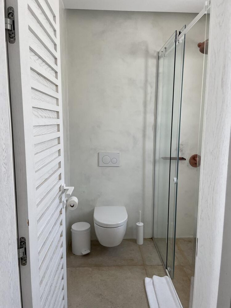 A bathroom with a glass shower door Description automatically generated